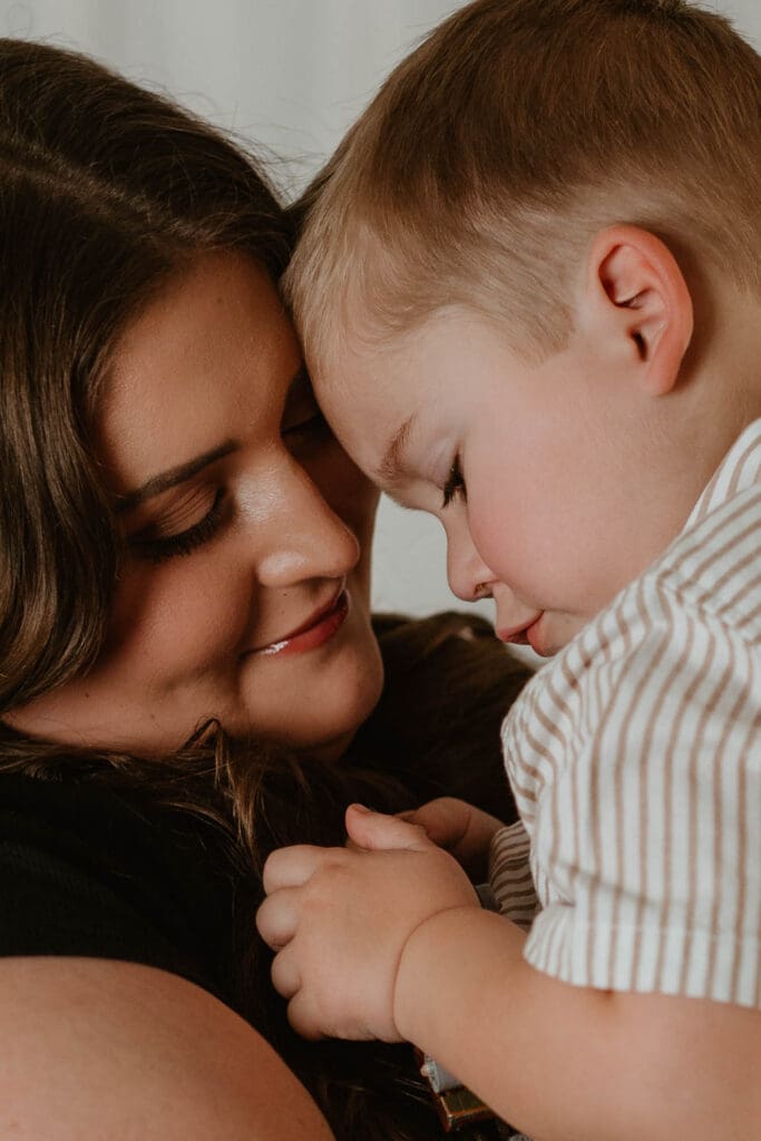 Mother and young son touching foreheads during indoor motherhood mini session in Southern Ohio