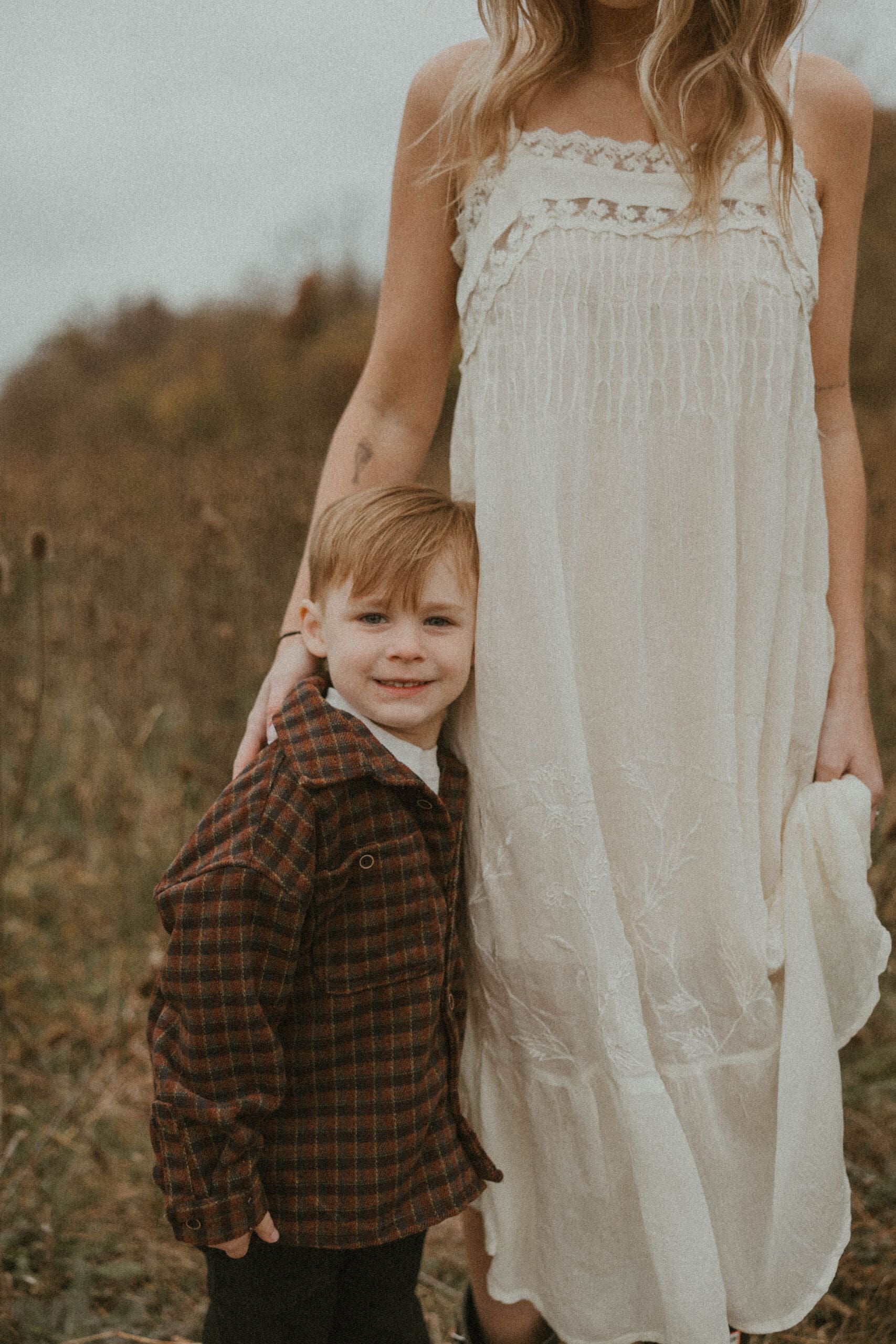 Young son hugging his mother’s leg during a vintage-style motherhood mini session in Southern Ohio
